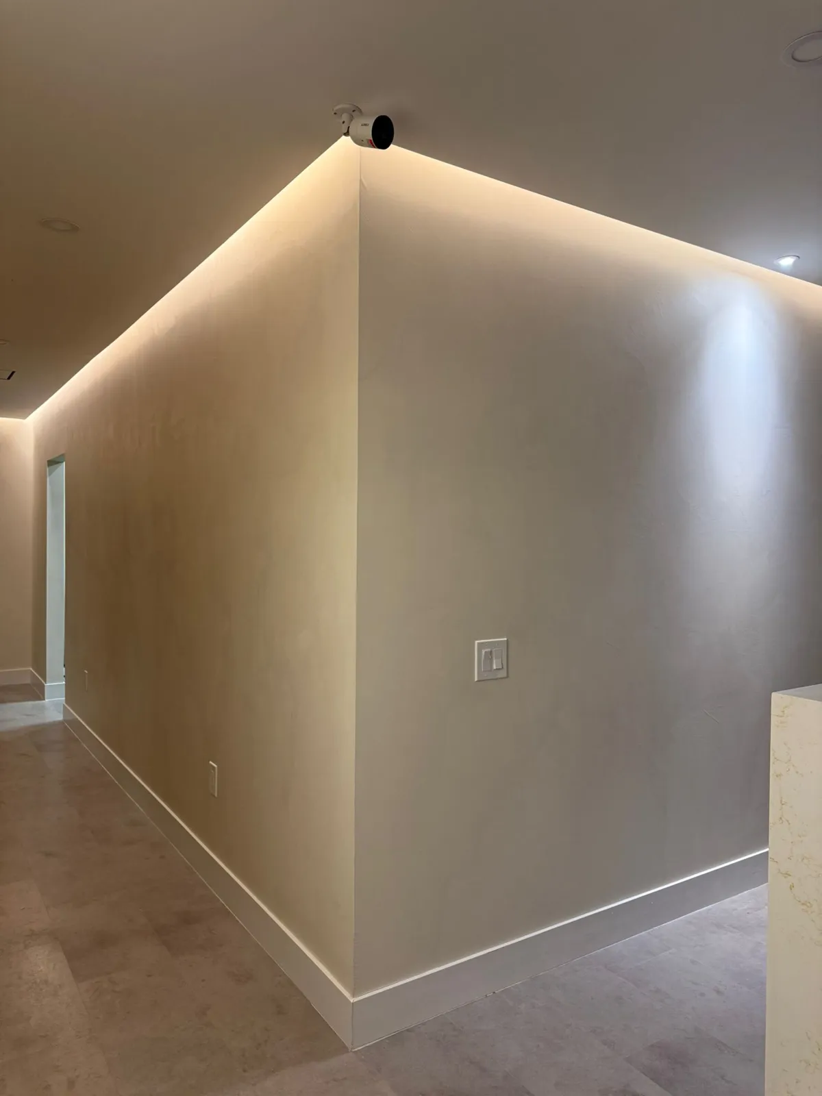 Hallway with hand-trowelled microcement walls under cove lighting